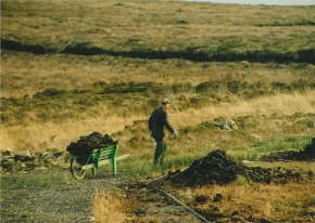 Donegal man carting turf in a wheelbarrow